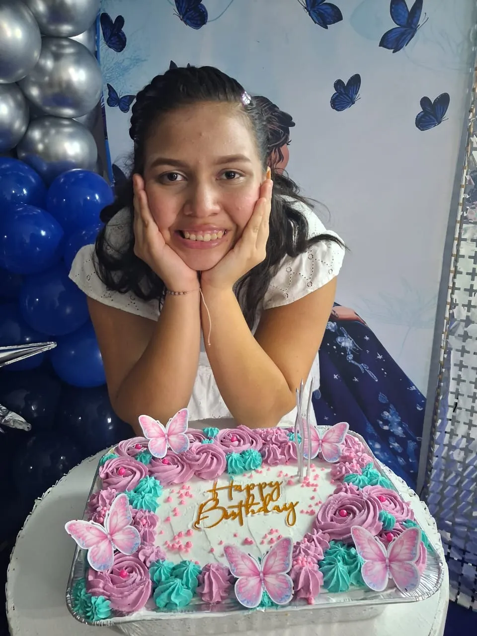 Alimar celebrando su cumpleaños de 19 años sonriente frente al stand decorado por Mayra