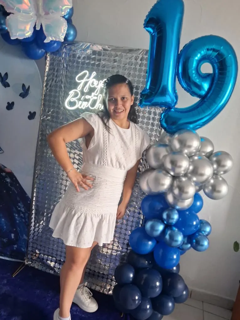 Alimar posando en el stand decorado de 19 años con arco de globos y decoración floral