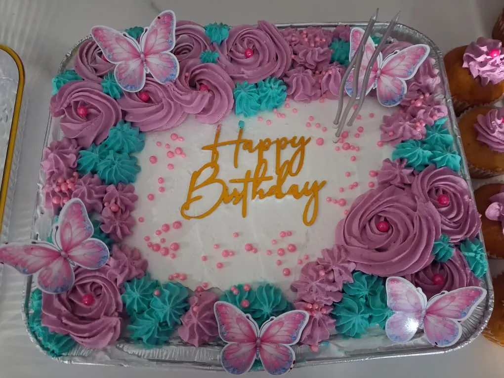 Torta tres leches decorada con letras grandes, flores rosadas y mariposas artificiales en Caracas (vista adicional)
